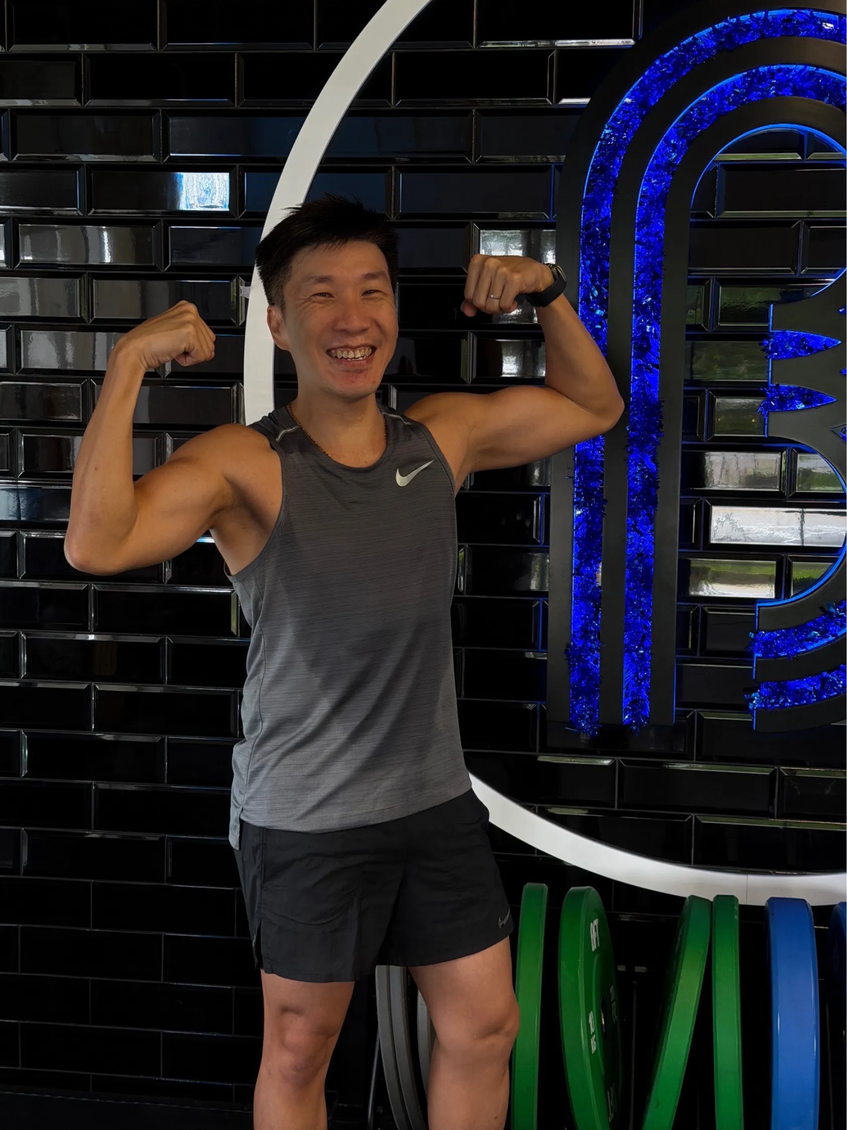 Clarry smiling and flexing his arms at the gym