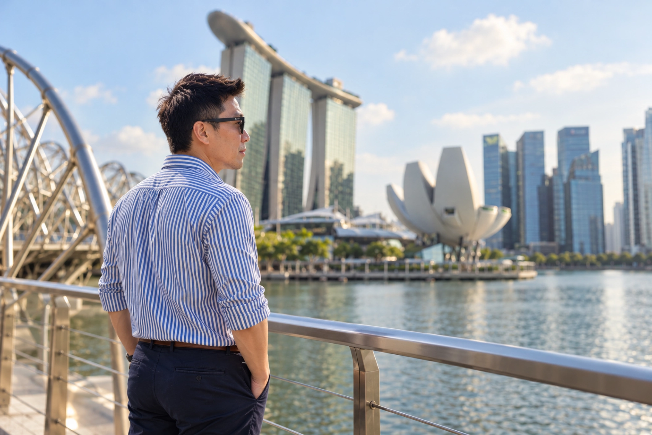 Clarry Au looking across Marina Bay in a blue striped shirt and Wayfarer sunglasses